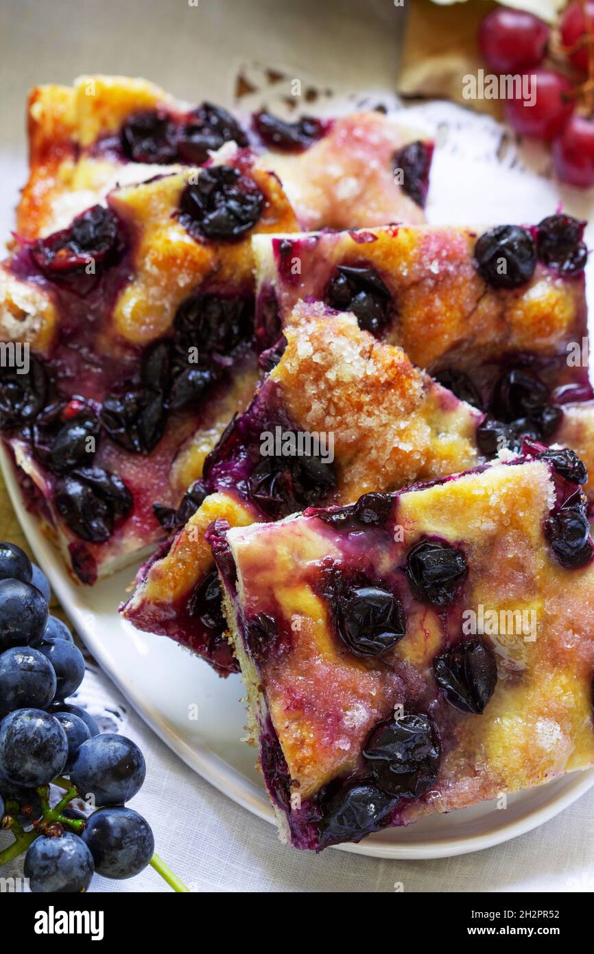 Traditional Italian yeast dough pie with grapes Schiacciata and bunches of grapes on a light background. Stock Photo