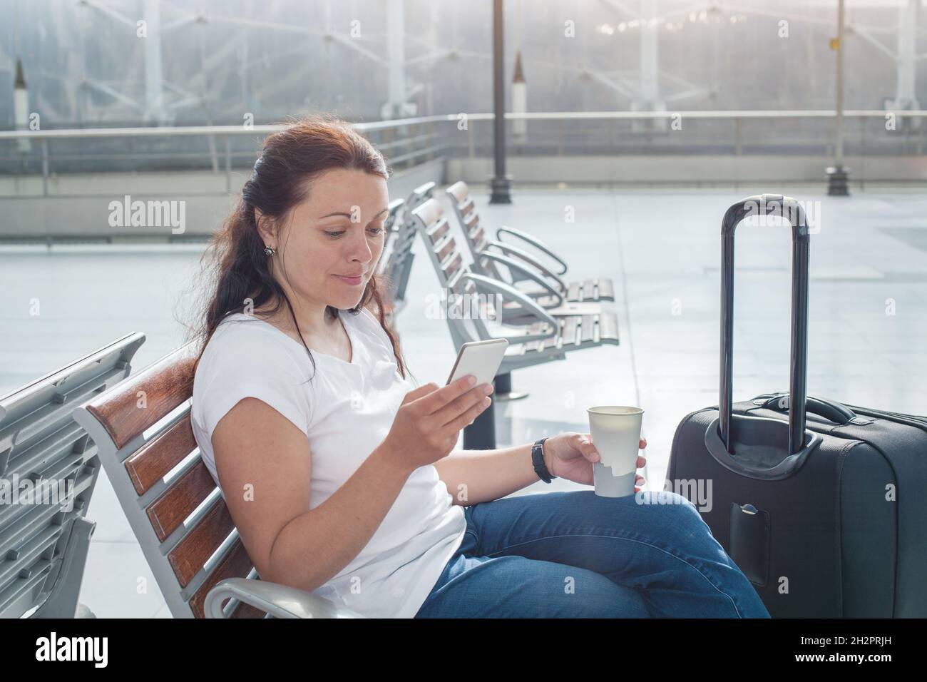 travel app, woman using mobile smart phone in airport, passenger waiting in gate terminal or railway station Stock Photo