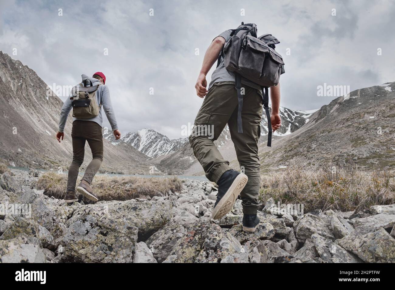 Two young hikers or tourists with small backpacks walks in mountains. Active tourism concept Stock Photo