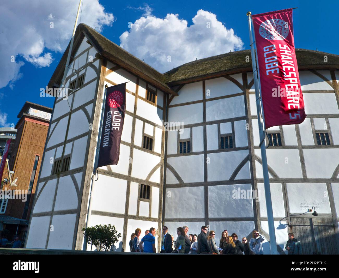The Shakespeare Globe Theatre with visitors taking a break outside. London SouthBank South Bank River Thames England UK Stock Photo