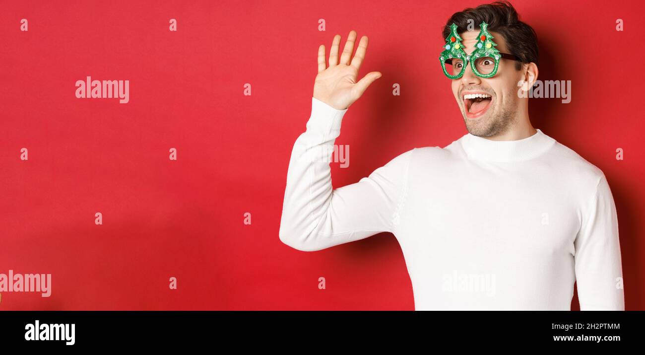 Portrait of friendly, cheerful man in party glasses and white sweater ...