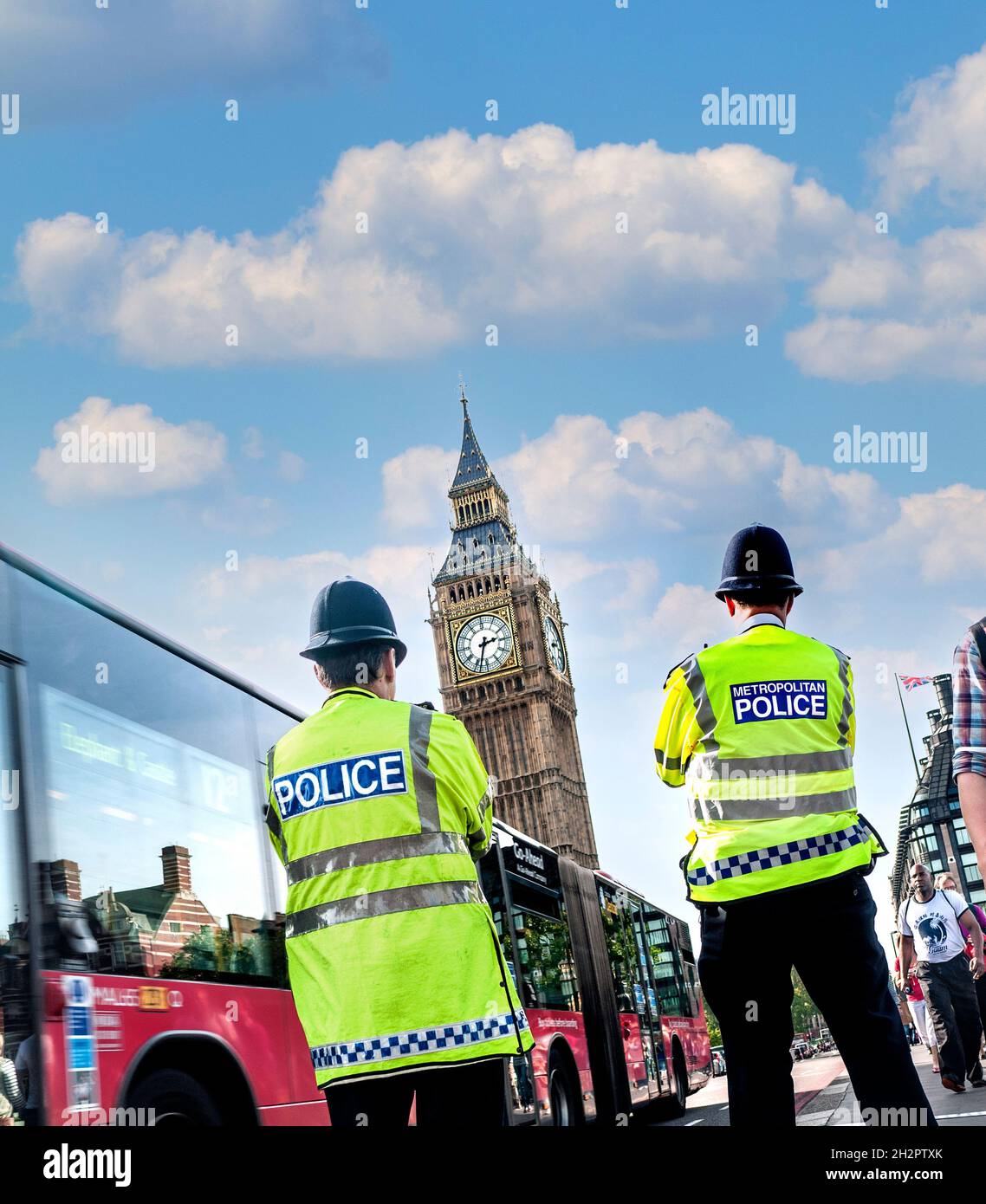 London Police officers wearing helmets and high visibility jackets on Westminster street duty back view at Westminster Bridge Houses of Parliament London UK Stock Photo