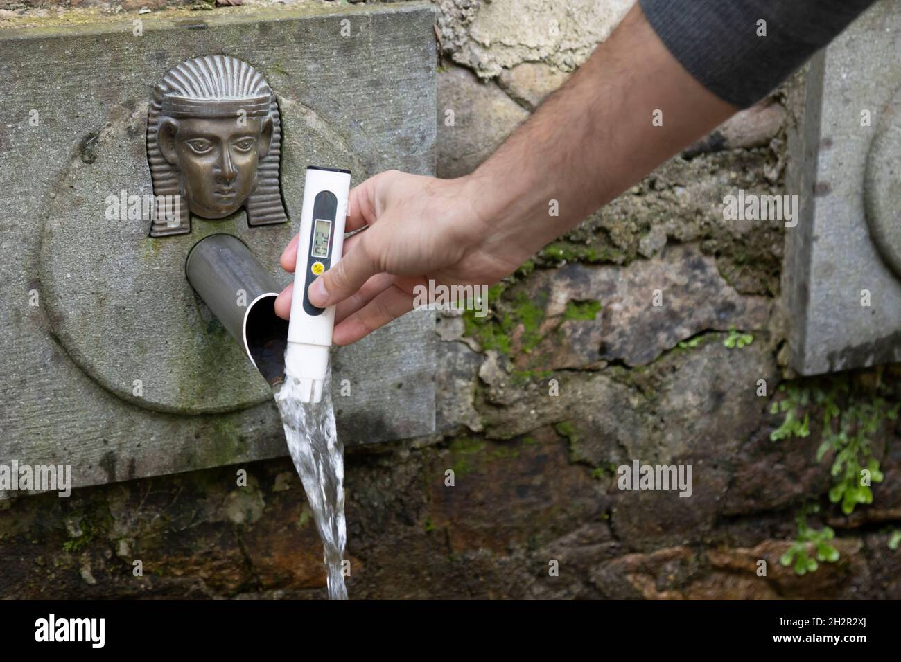 man measures the water quality of a natural spring with tester Stock Photo