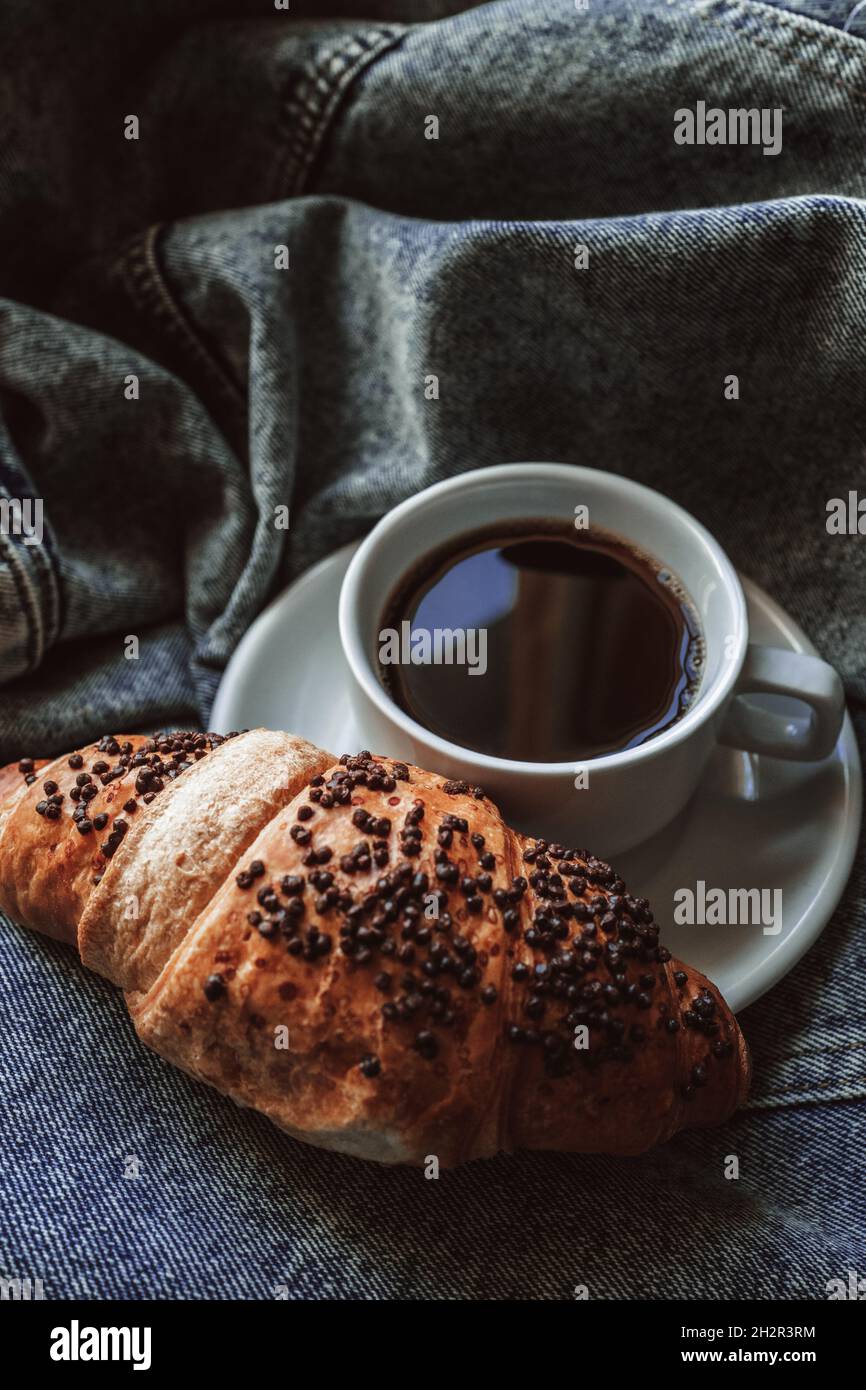 Aromatic black coffee americano in white cup and fresh sweet croissant
