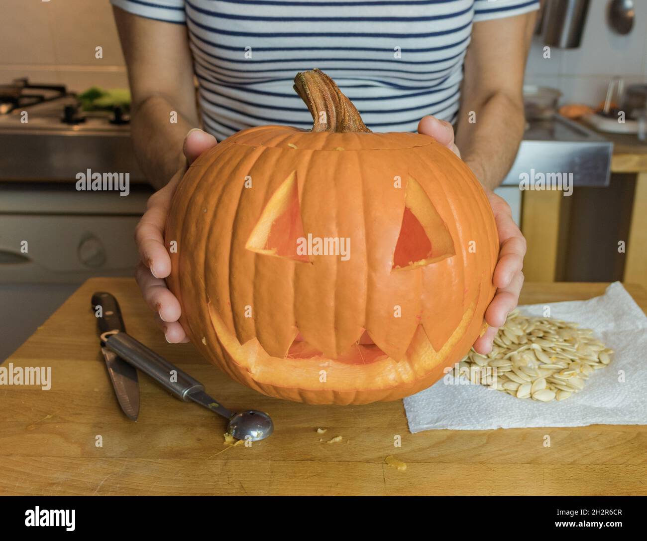 Pumpkin decorated and prepared for Halloween, human hands displaying pumpkin Stock Photo
