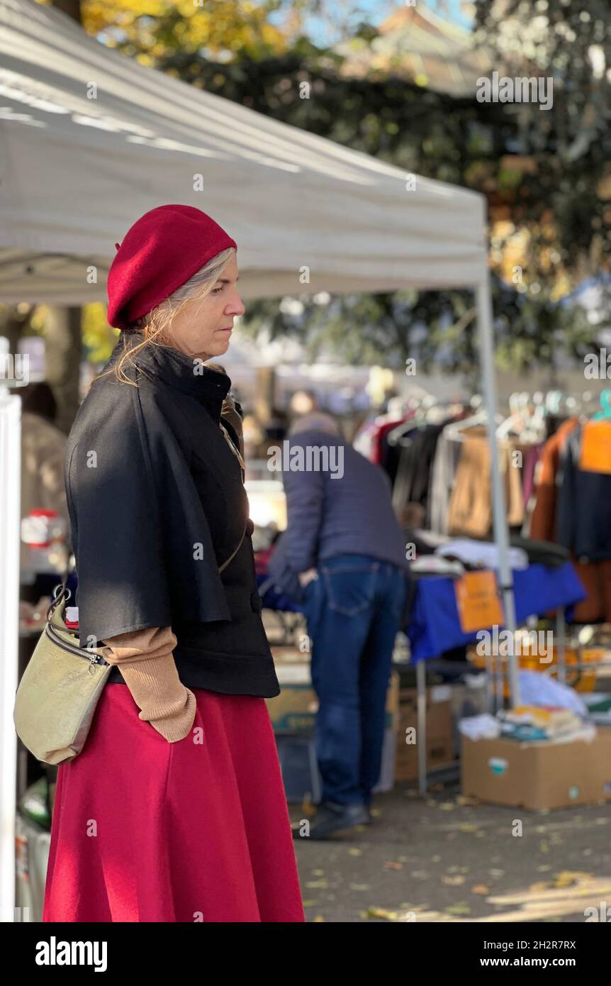 Middle aged woman in vintage clothes at flea market. Her face expression ist tense, she does not look happy and she is thinking about something. Stock Photo