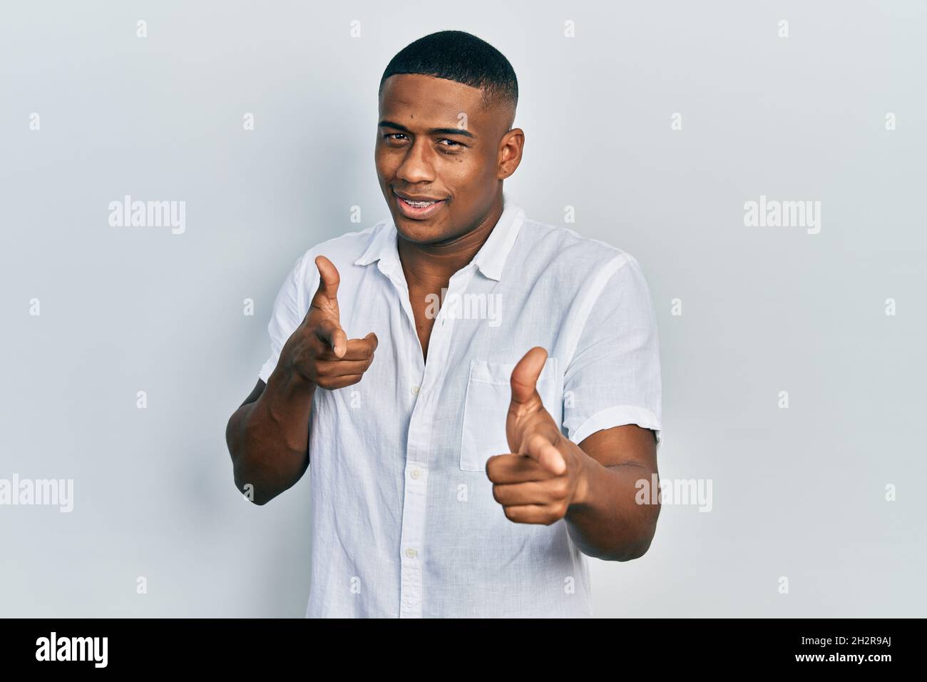 Young black man wearing casual white shirt pointing fingers to camera ...