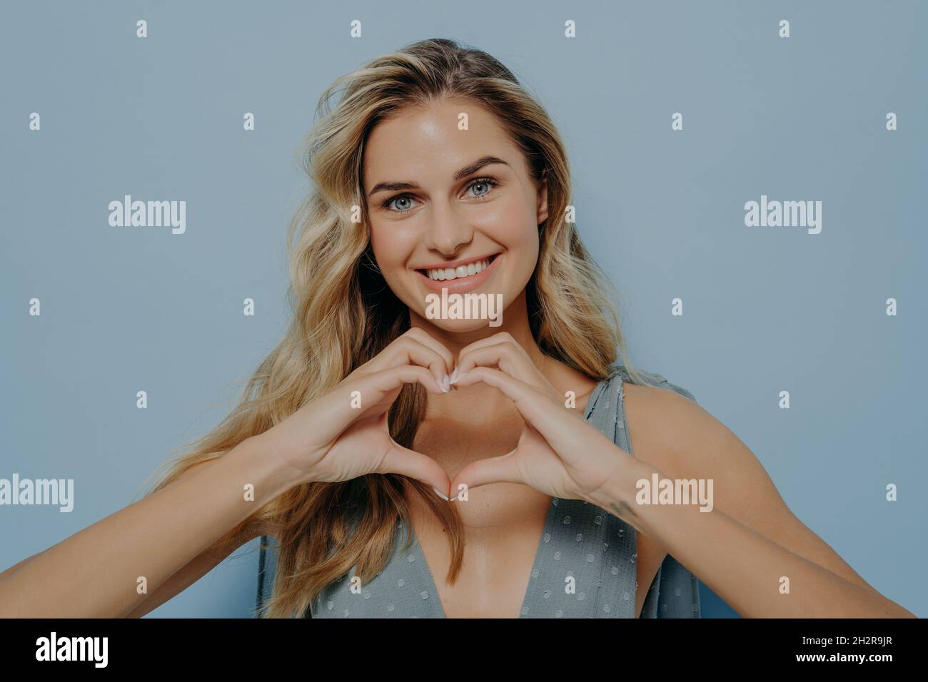 Lovely blonde woman admitting in her love with use of heart gesture Stock Photo