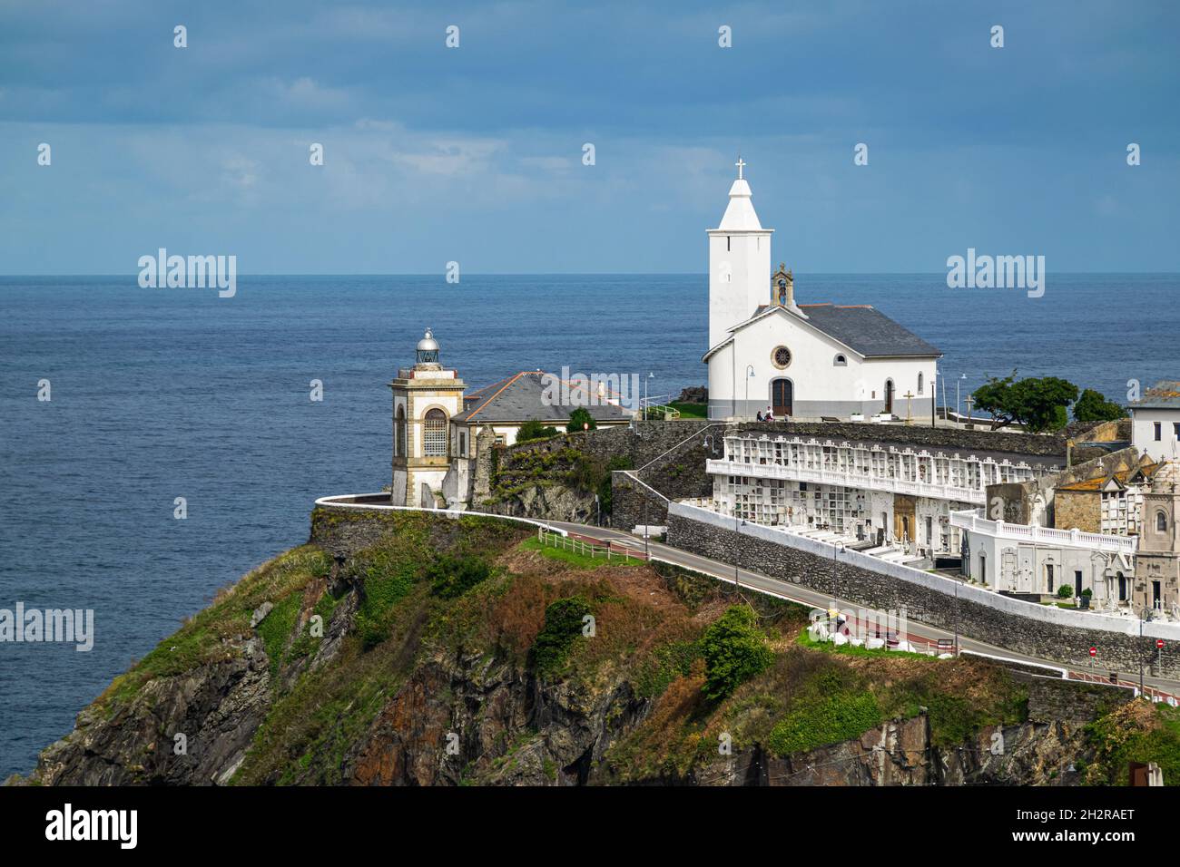 Picturesque chapel with cemetery and a lighthouse overlooking Bay of Biscay in the village of Luarca, Asturias, Spain. Stock Photo