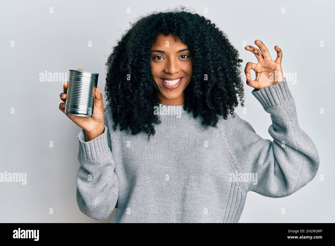 African american woman with afro hair holding canned food doing ok sign ...