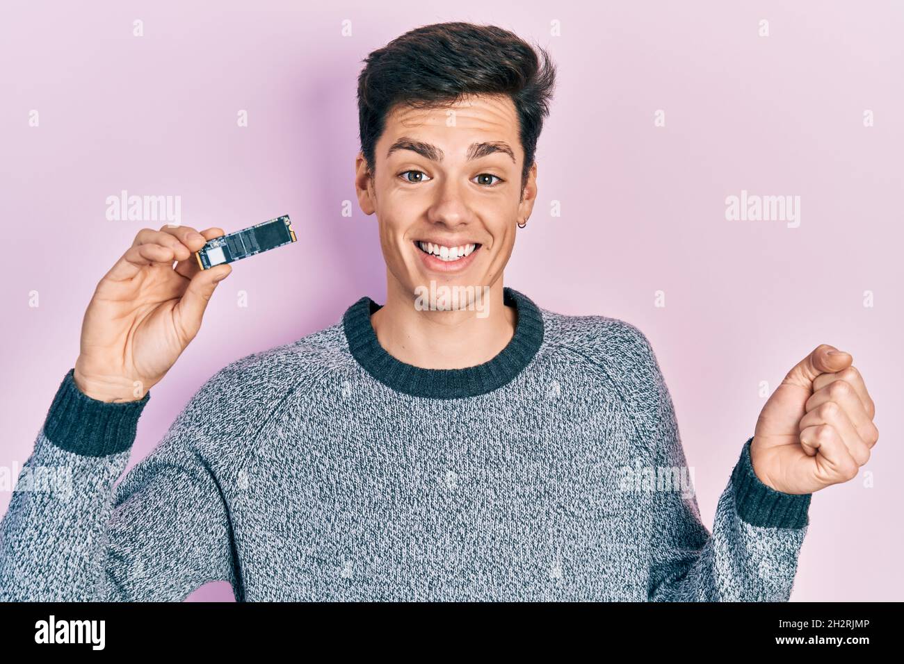 Young hispanic man holding ssd memory screaming proud, celebrating ...