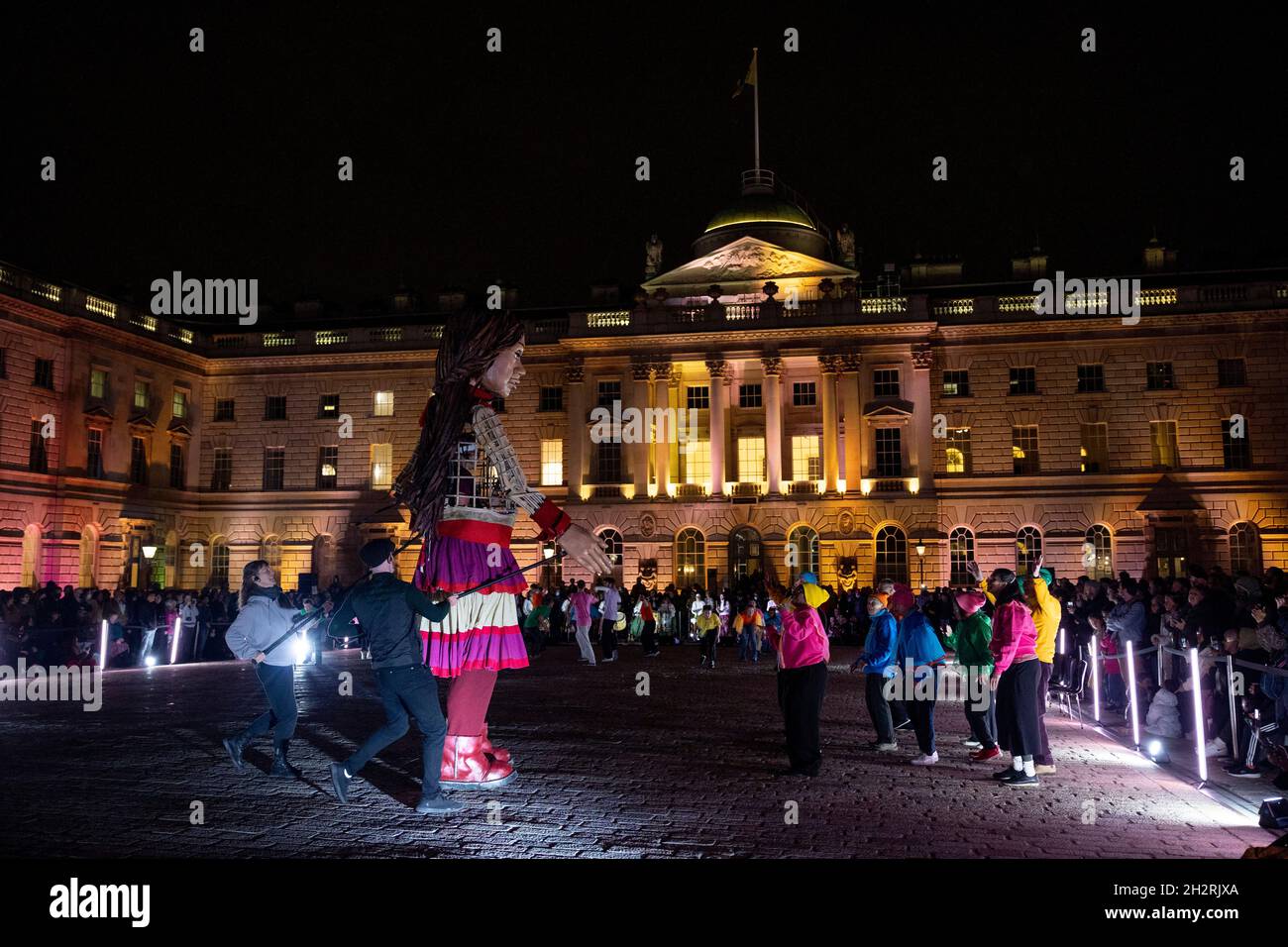 London, UK. 23rd Oct, 2021. Little Amal seen dancing with a group of performers outside the Somerset House.Little Amal is a 3.5 metre-tall puppet representing a Syrian refugee child, whose journey began close to the Turkish-Syrian border, travelling 8,000 km across Europe to the UK in support of refugees. Credit: SOPA Images Limited/Alamy Live News Stock Photo