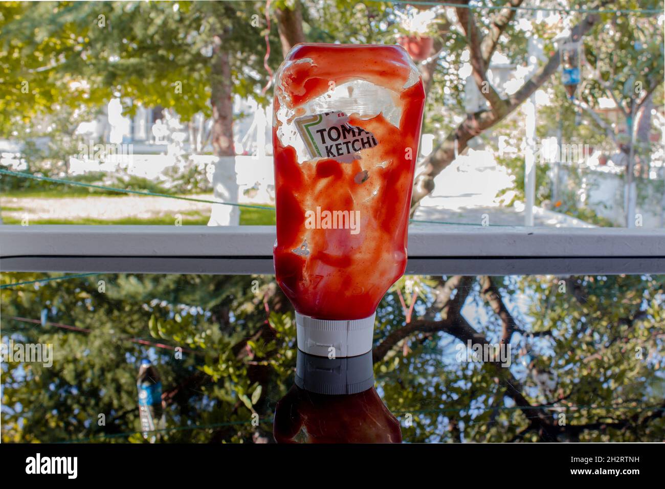 Slightly empty ketchup bottle on shiny table and wooden cutting board