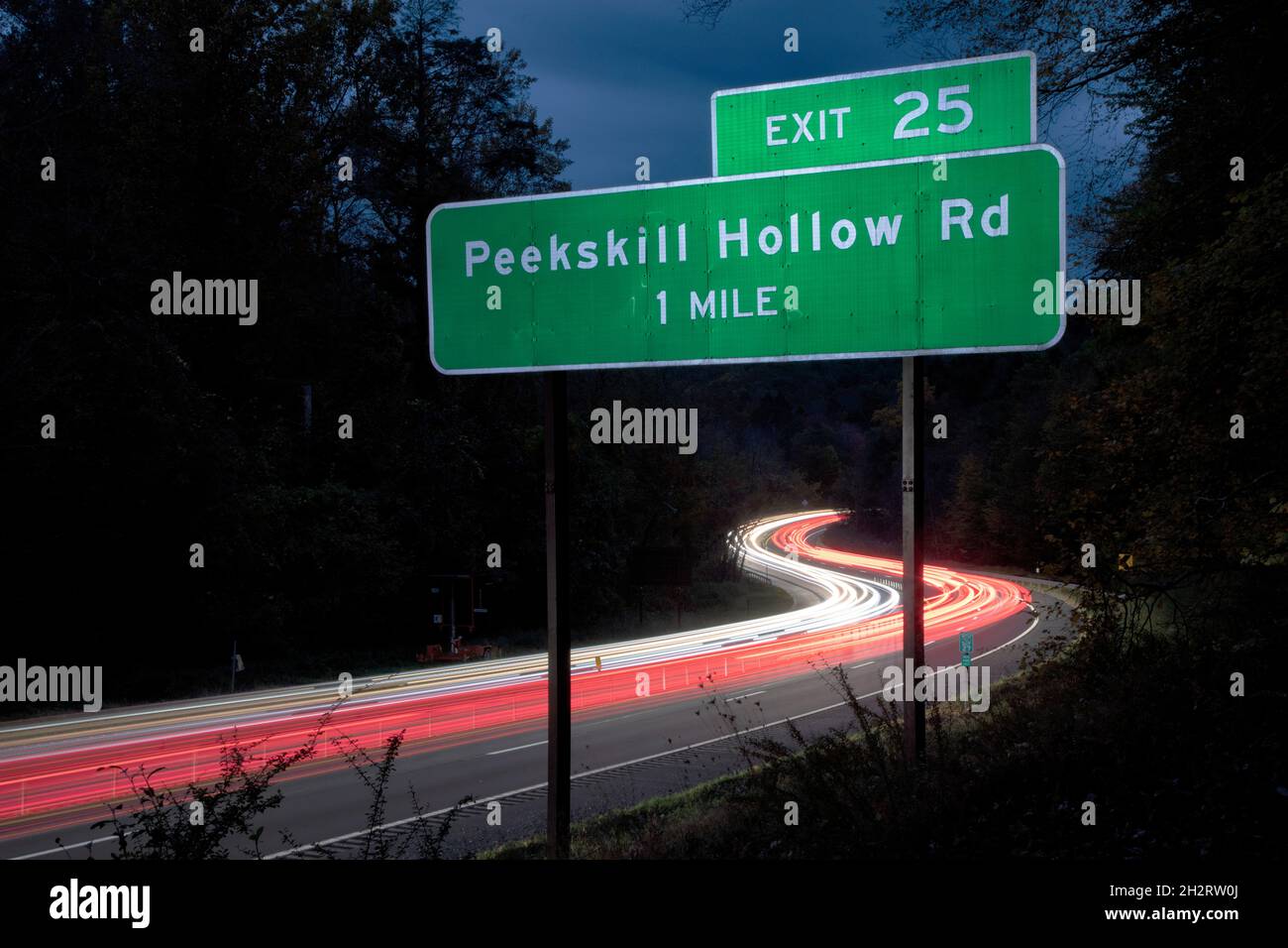 Rush Hour traffic blurred by a slow camera shutter speed on the Taconic State Parkway in Putnam County, New York. Peekskill Hollow Road exit sign. Stock Photo
