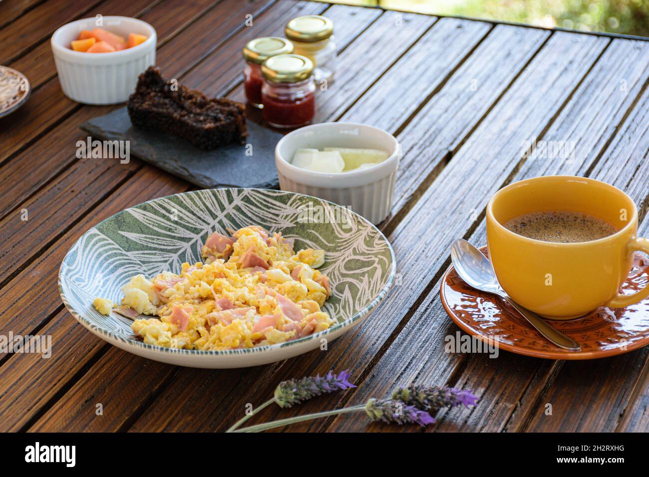 Breakfast. Eggs with ham, cup of coffee, melon portion and cookie cake (side view). Stock Photo