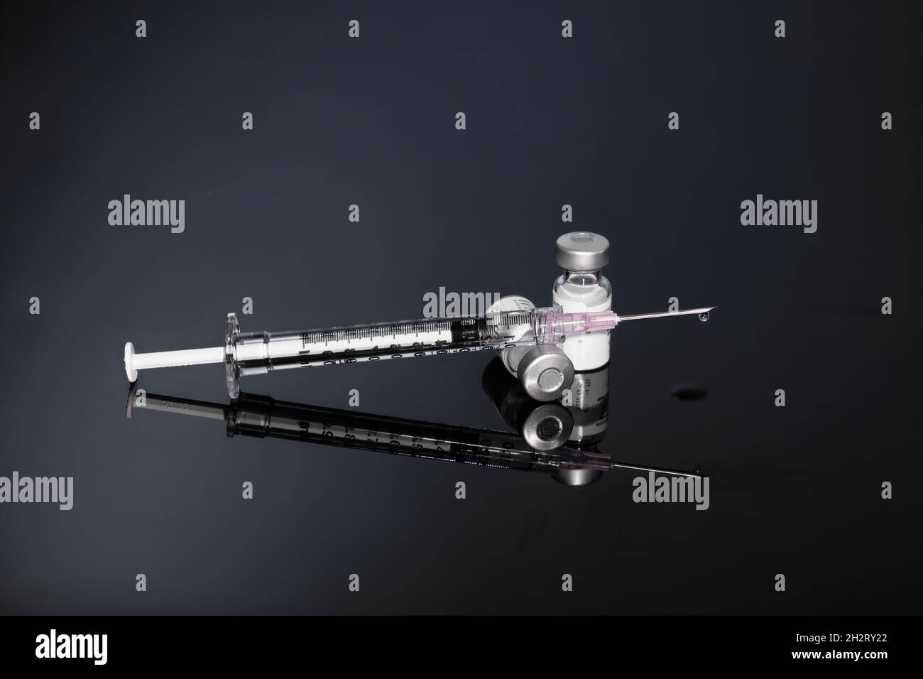 Syringe with vials and Needle on dark background Stock Photo