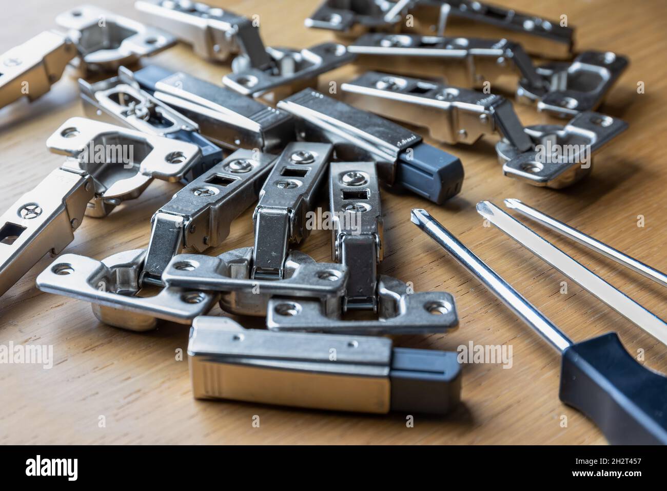 A pile of soft close cabinet door hinges and screwdrivers Stock Photo