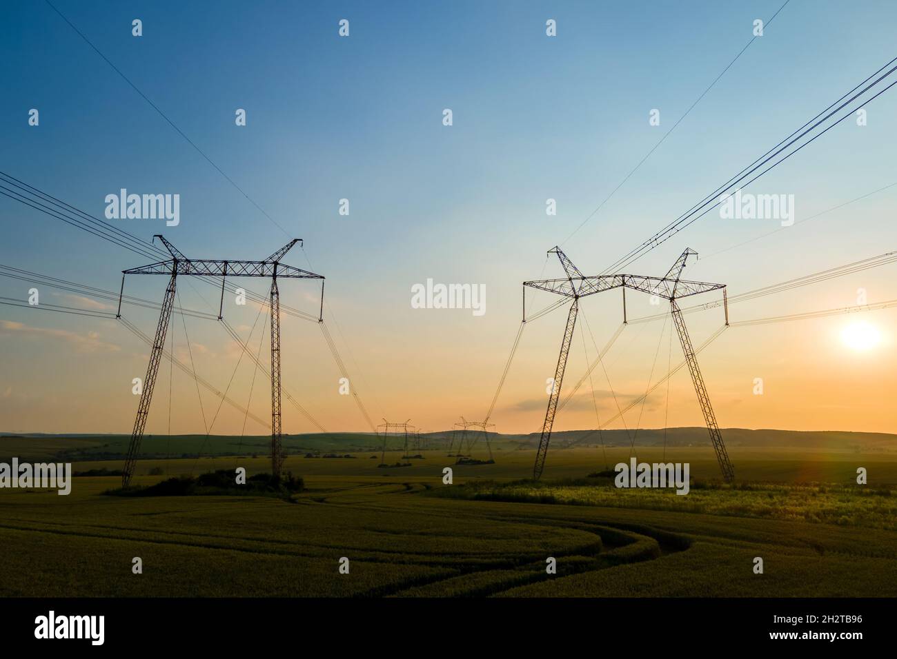 Dark silhouette of high voltage towers with electric power lines at ...