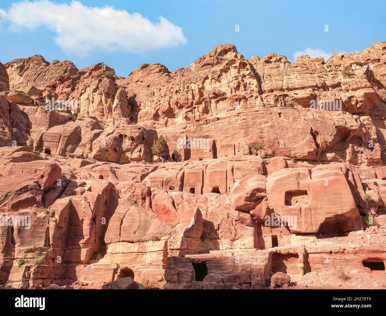 Ancient housing carved in red sand rock in the city of Petra, Jordan. Detail with Tomb of 'Unayshu Stock Photo