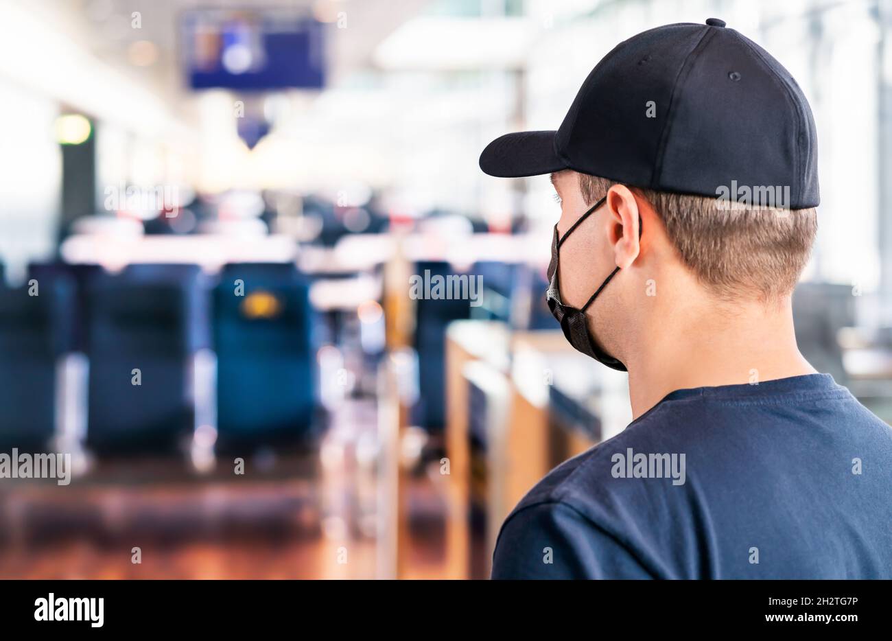 Mask at airport. Man waiting for flight in terminal. Corona virus, covid19 and travel. Tourist wearing facemask during pandemic at gate. Stock Photo