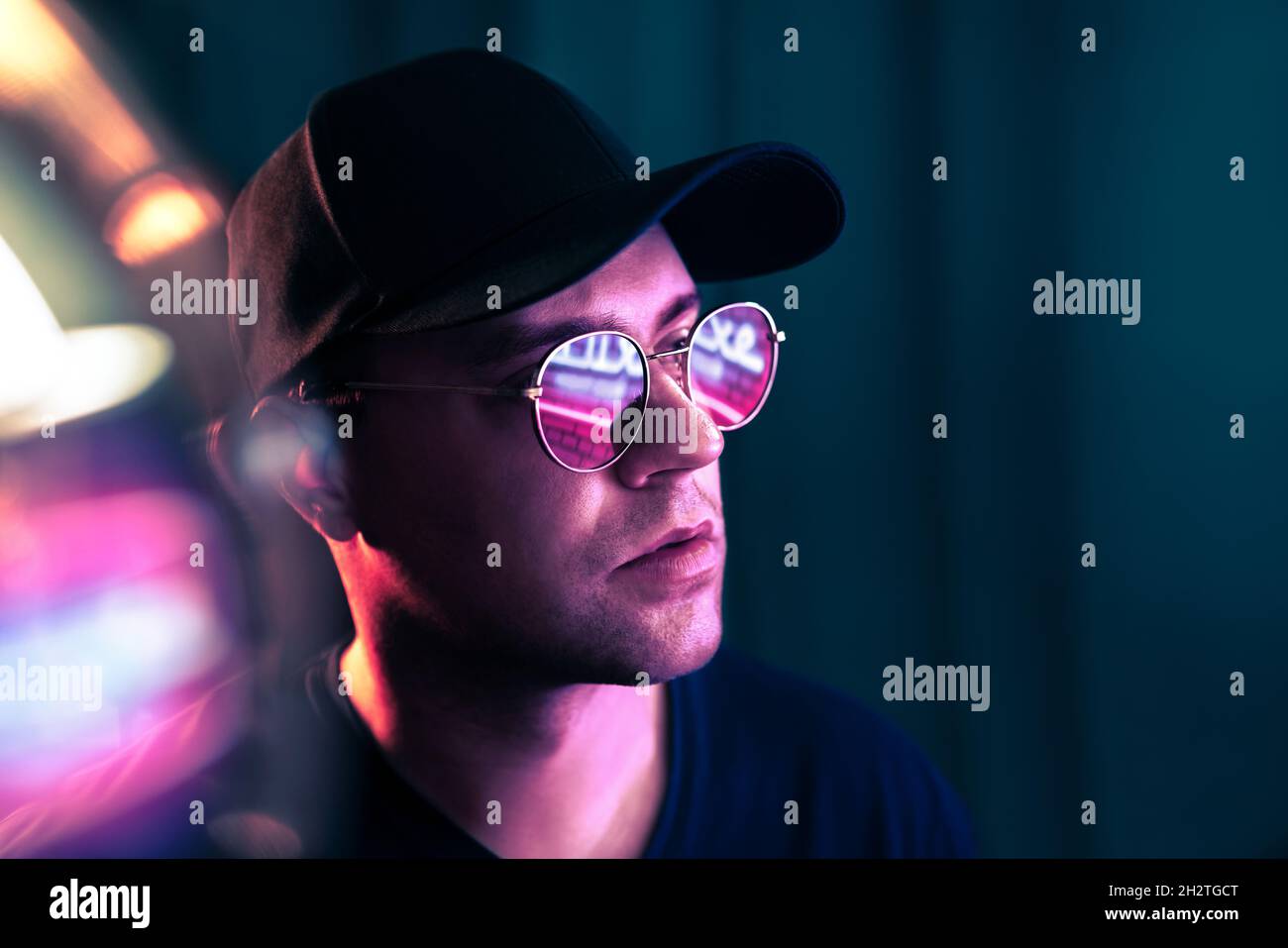Futuristic neon technology. Man with glasses in future cyberpunk illumination. Purple fluorescent color on face. Studio portrait. Techno rave party. Stock Photo