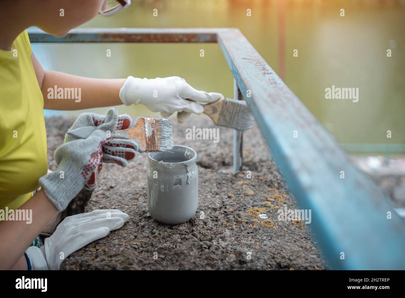 volunteer worker painting with brush or roller and renovate railing or fence Stock Photo