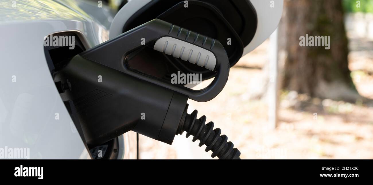 View of new white electric car charging at a station Stock Photo