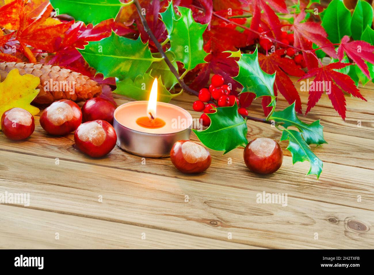 Natural Autumn decoration and burning candle on wooden background Stock Photo