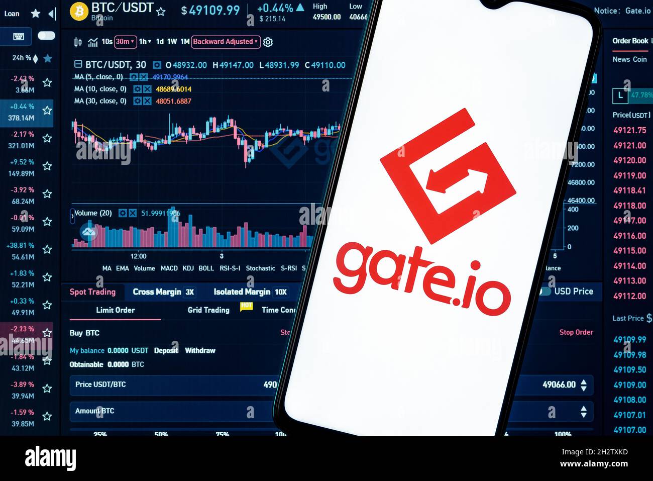A smartphone with the Gate.io logo on the background of the live trading webpage. Gate.io dashboard. Stock Photo