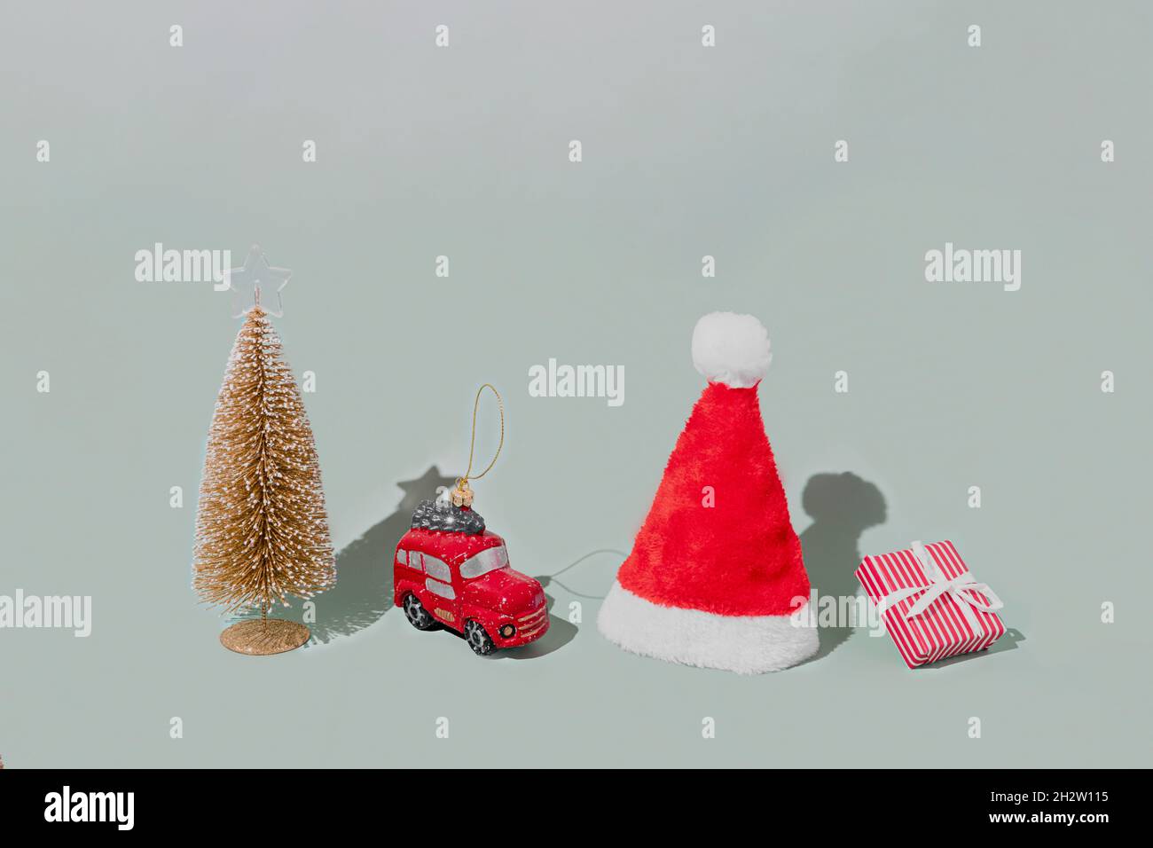 Gray background with Christmas or New Year symbol attribute objects and symbolic items concept. Pink gift box present with ribbon, small red taxi car Stock Photo