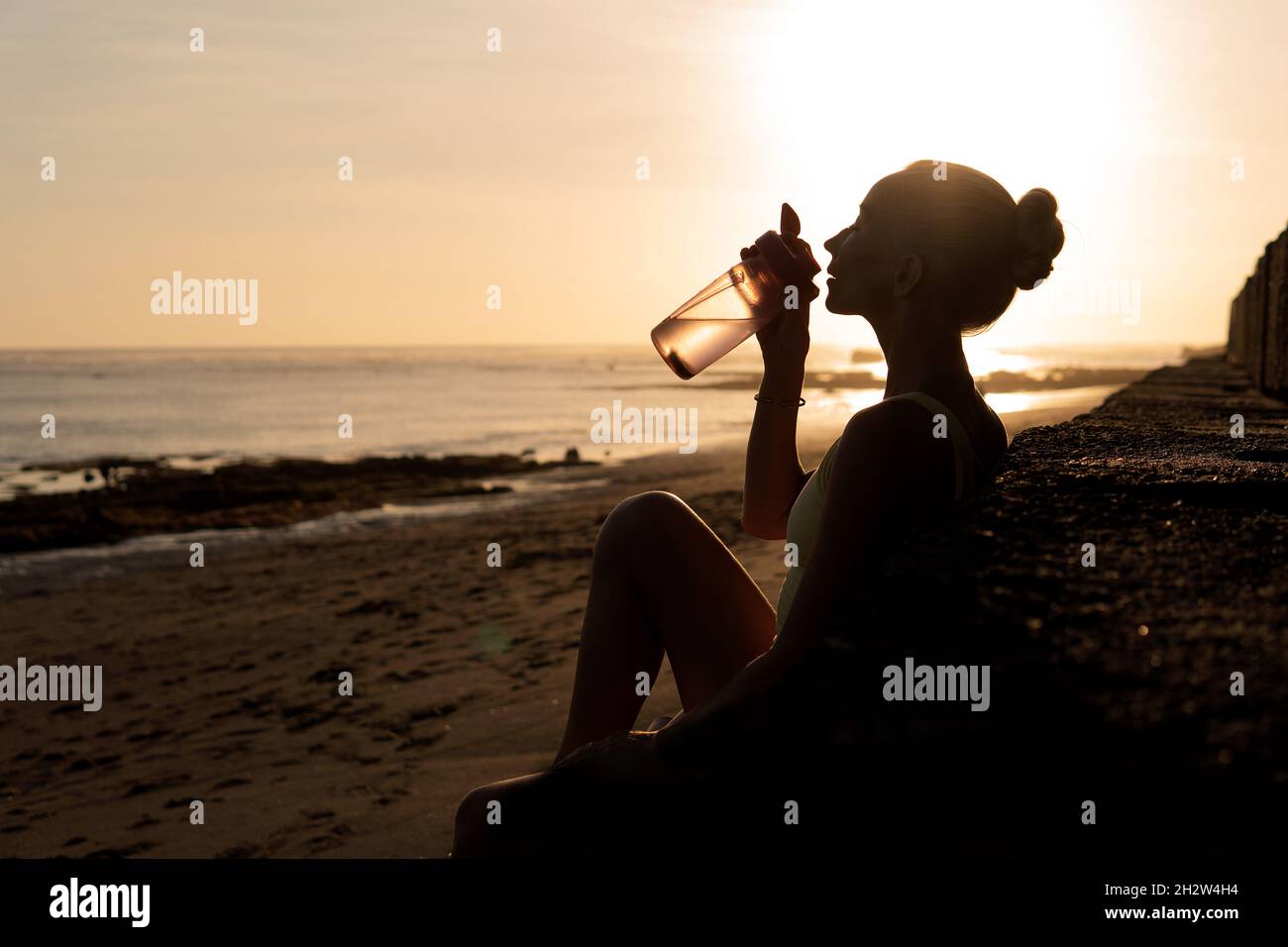 beautiful young woman drinking water. bali sunset Stock Photo Alamy