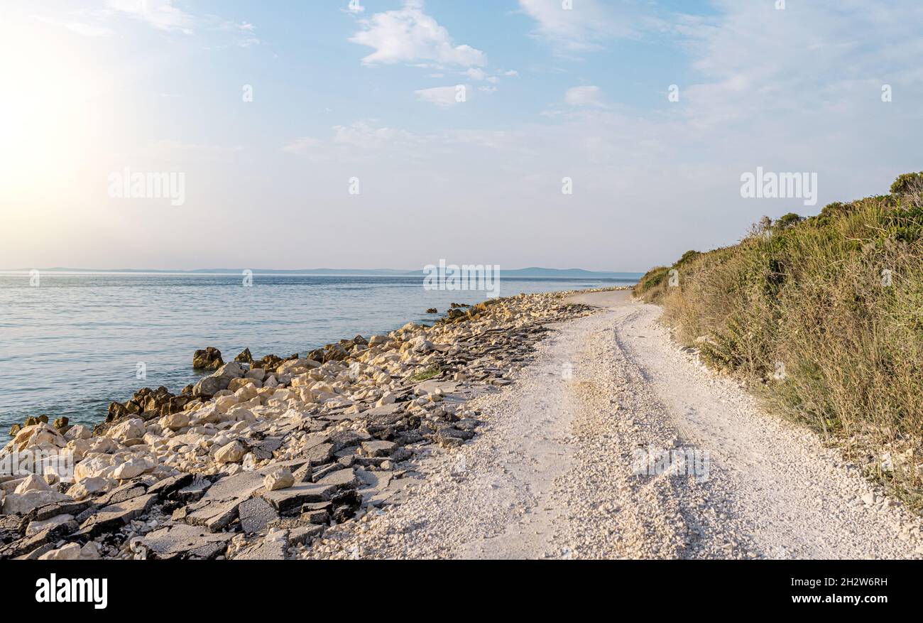Country road on the seashore in the rays of sunset. Stock Photo