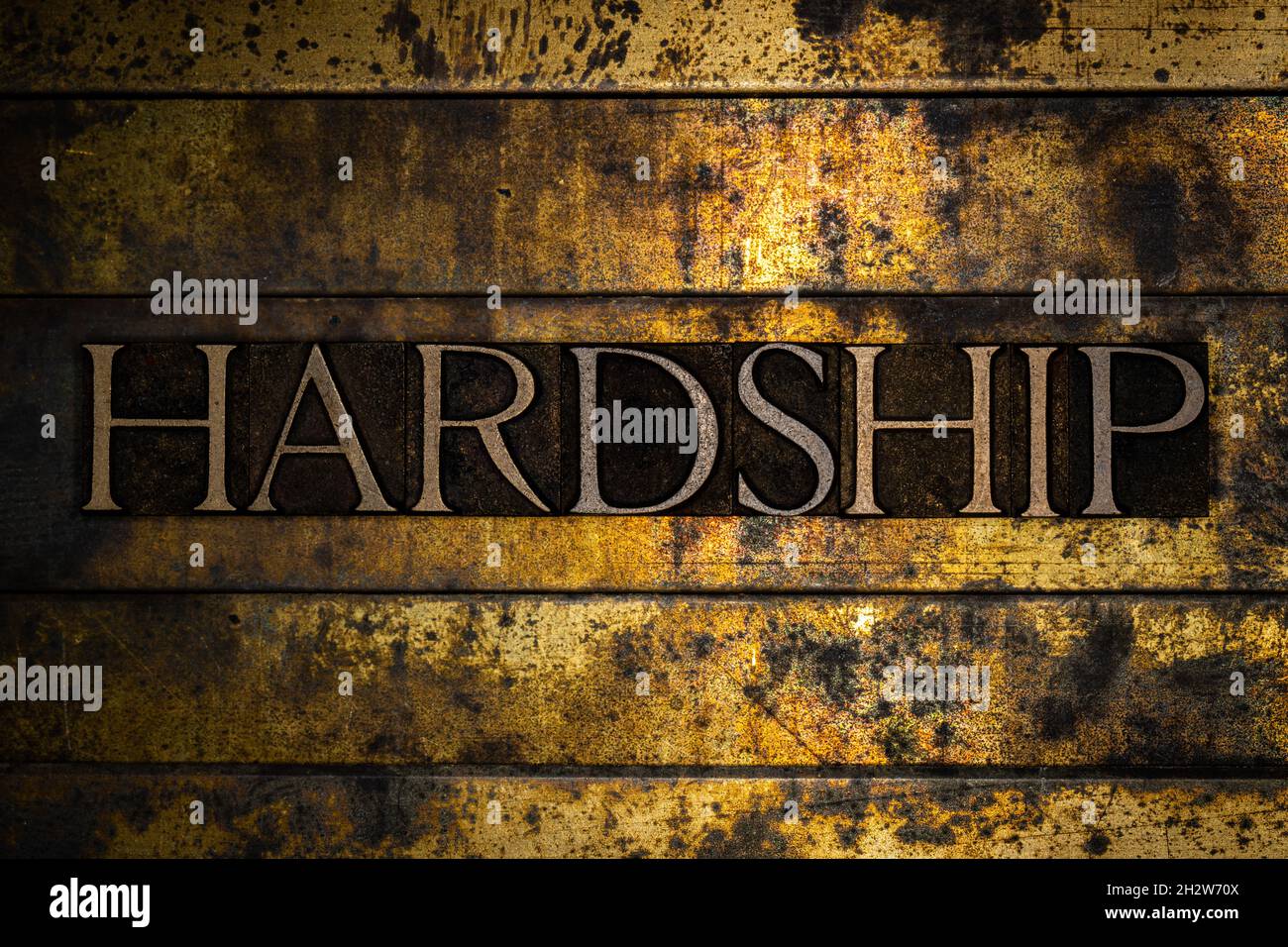 Hardship text on textured grunge copper and vintage gold background Stock Photo