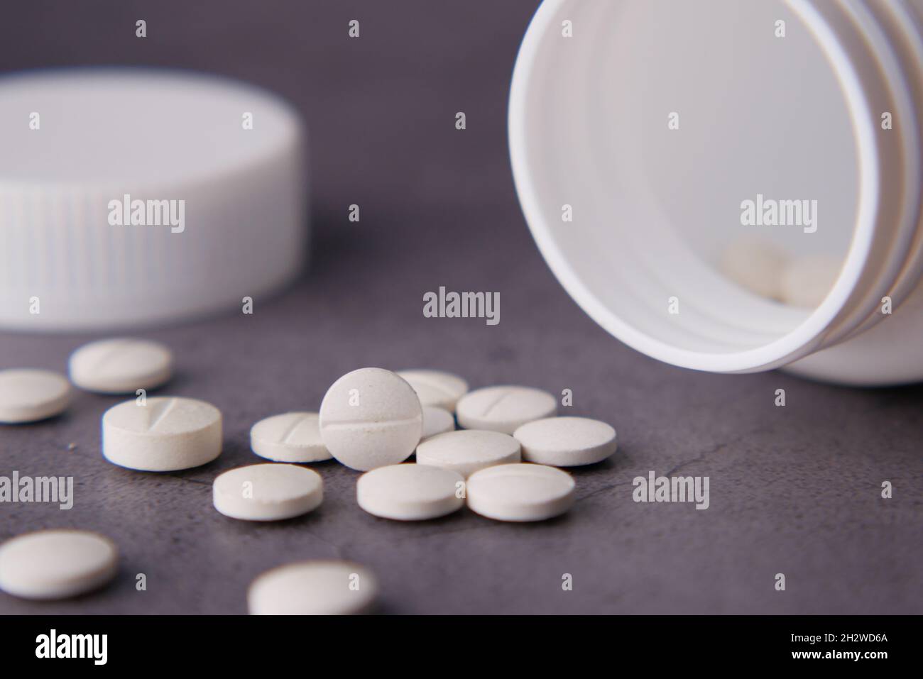 white color medical pills spilling on black background Stock Photo - Alamy