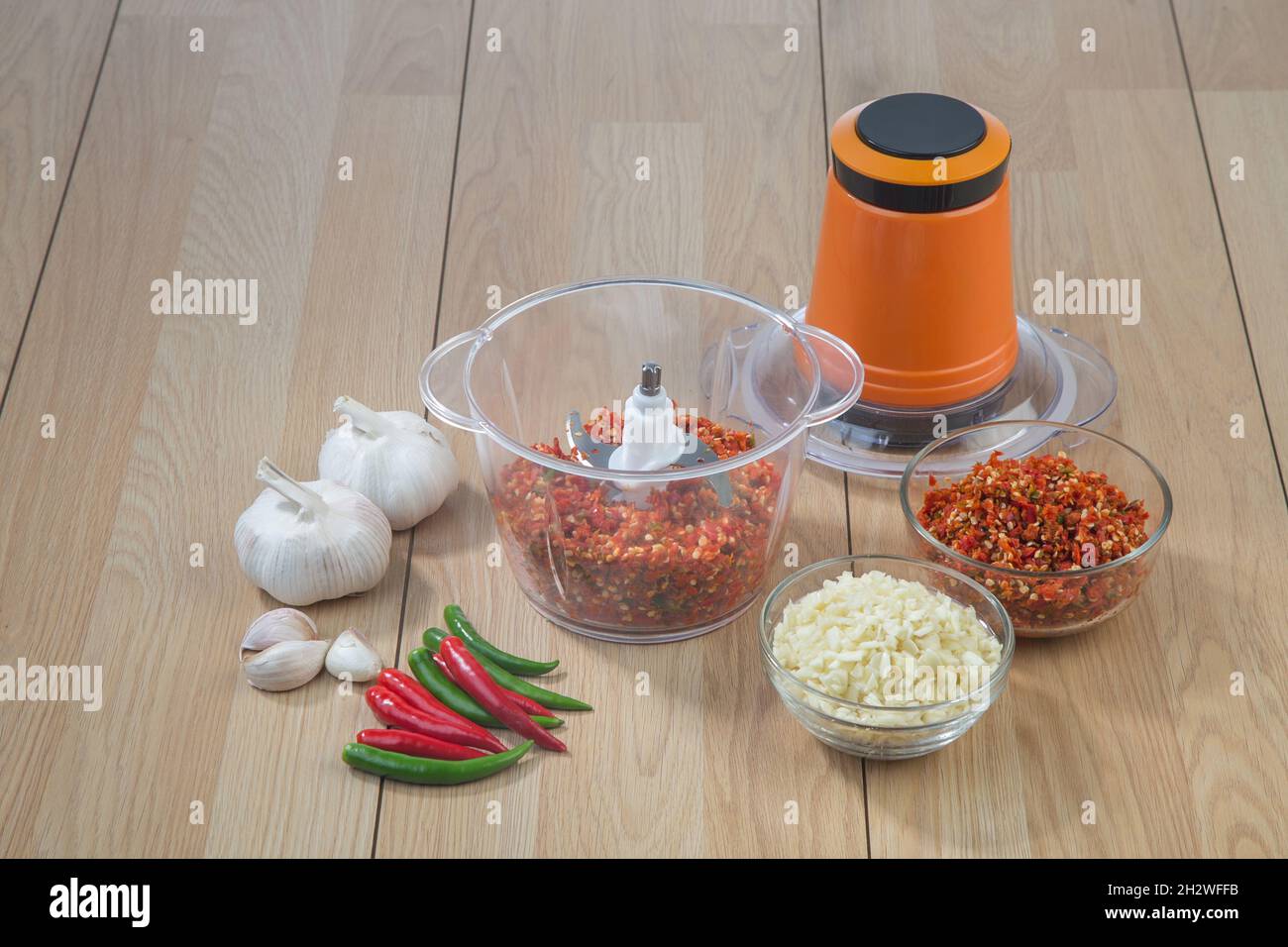 Food processor with chopped chilli and garlic on wooden table