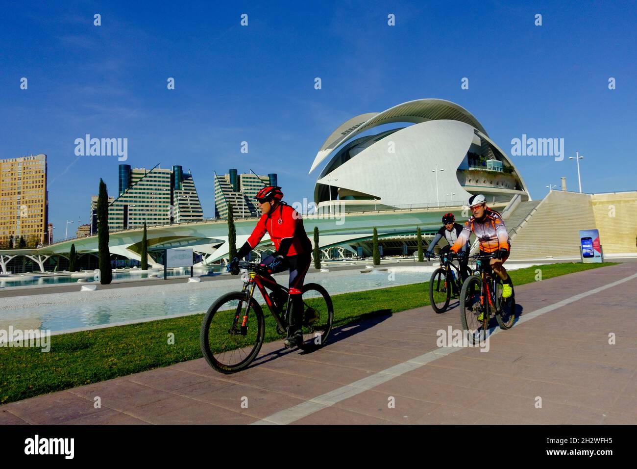 Valencia City of Arts and Sciences, men riding bikes, Valencia Turia Park People biking in modern Spain city architecture Stock Photo