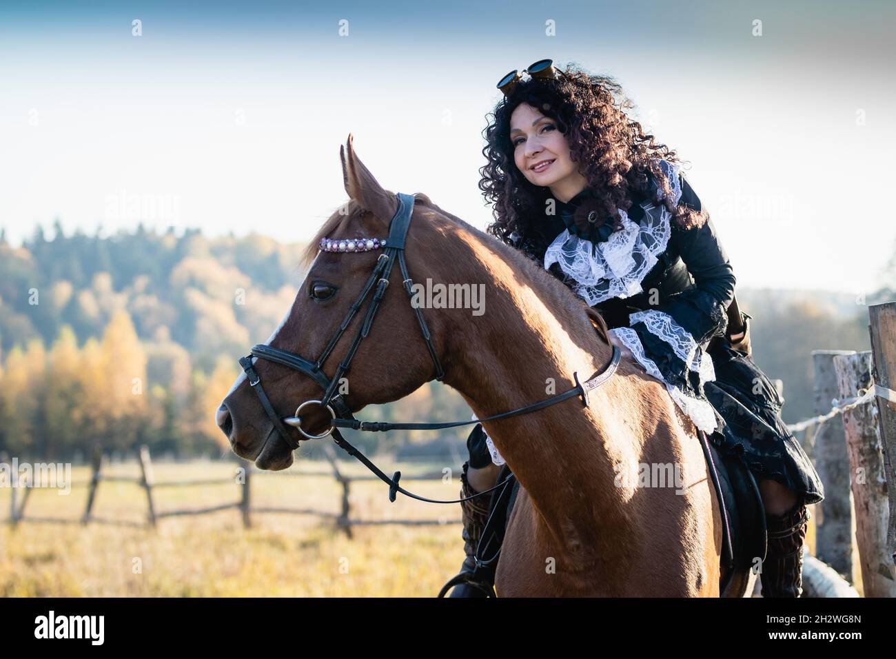 Portrait of a mature woman in a steampunk costume on a horse against the backdrop of an autumn landscape. Stock Photo