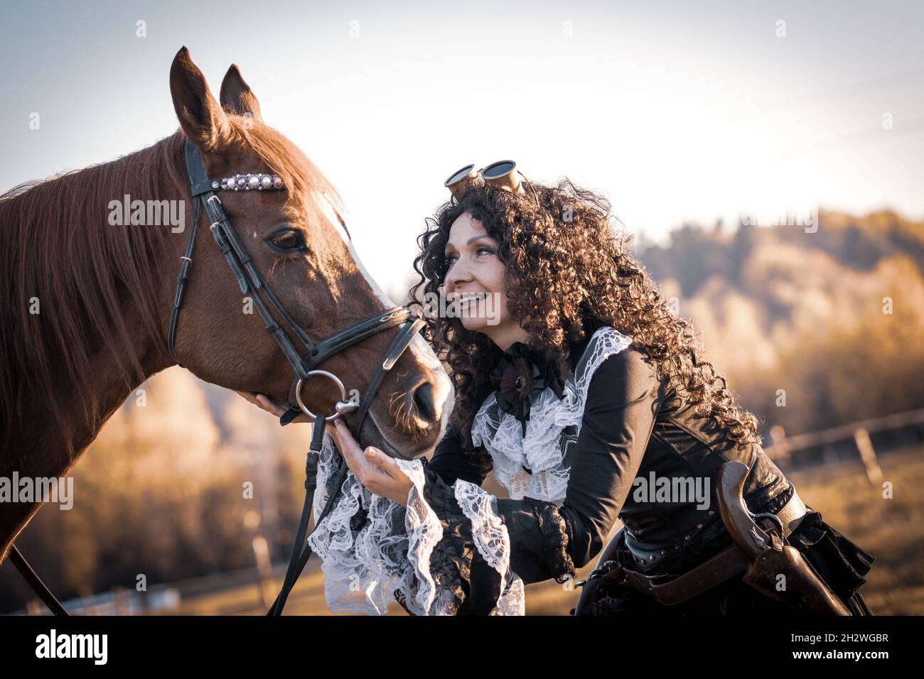 Portrait of a mature woman in a steampunk with a horse against the backdrop of an autumn landscape. Stock Photo