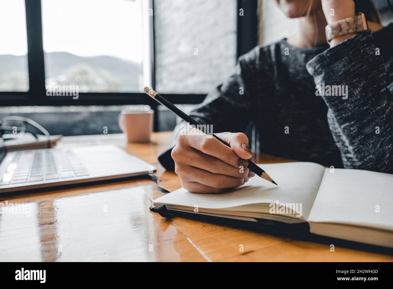 Close up of student girl hand writing on notebook on a desk at home. Stock Photo