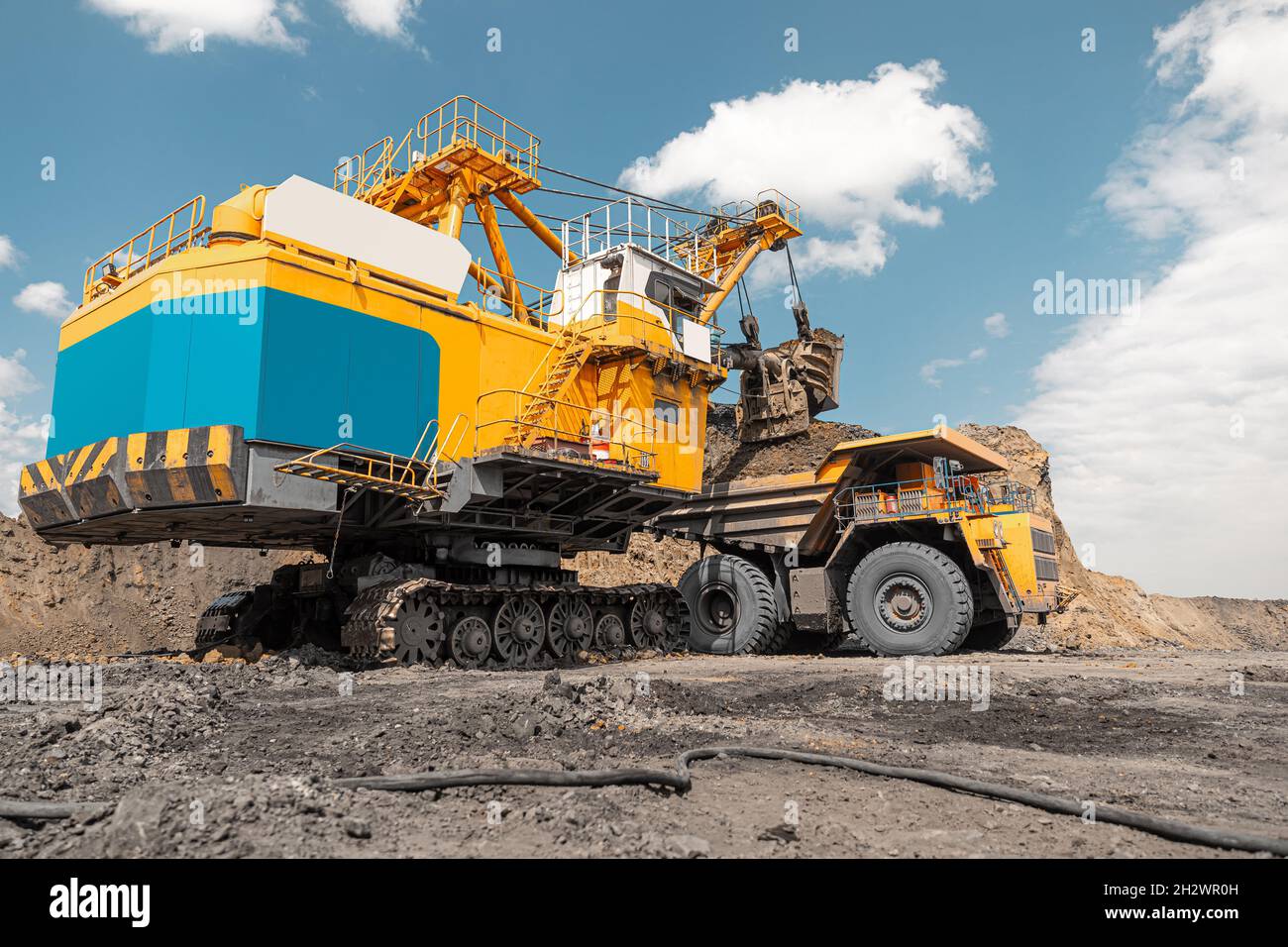 Large quarry dump truck. Big yellow mining truck at work site. Loading