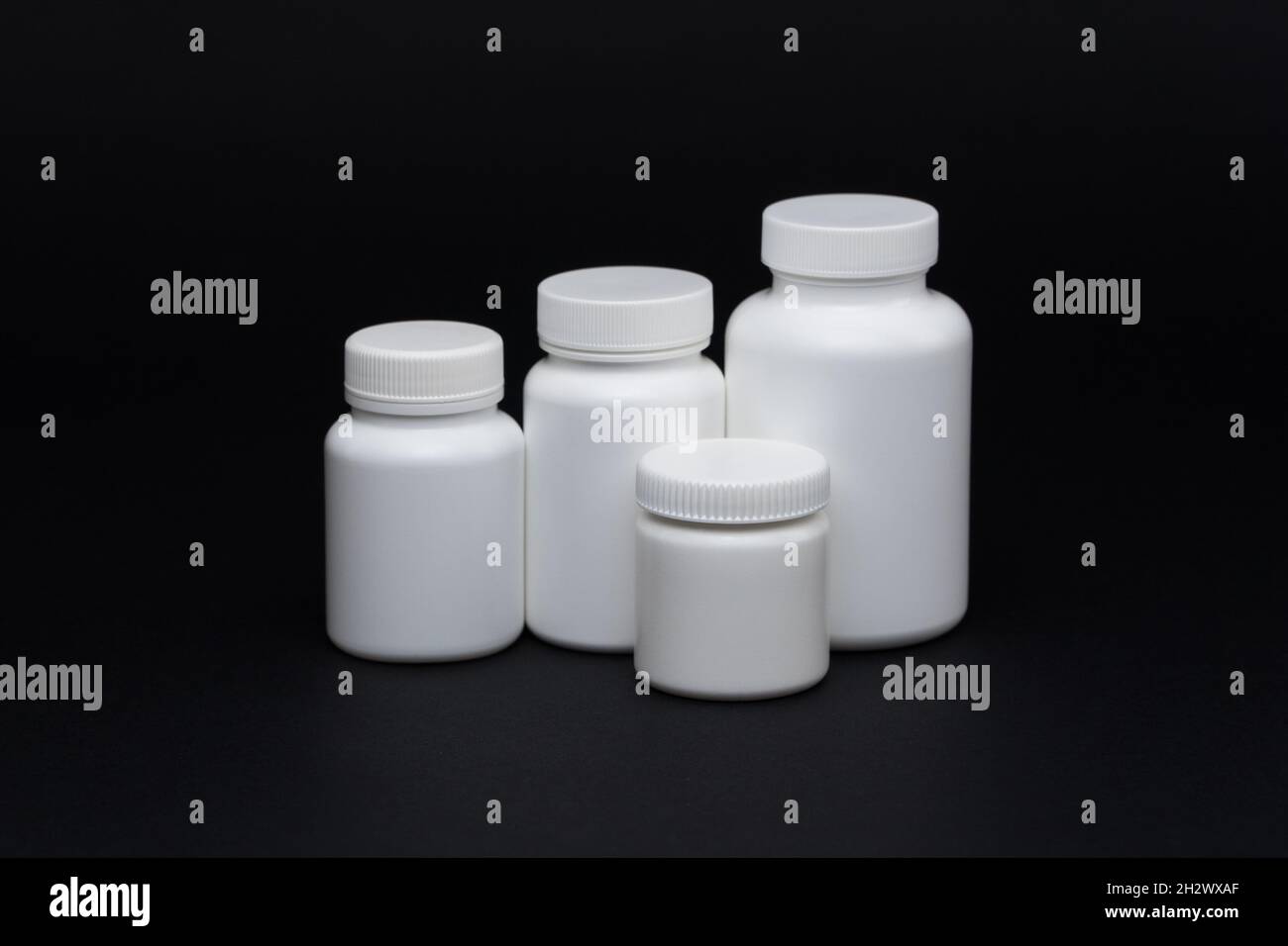 White plastic pill jars on a black background. Isolated Stock Photo