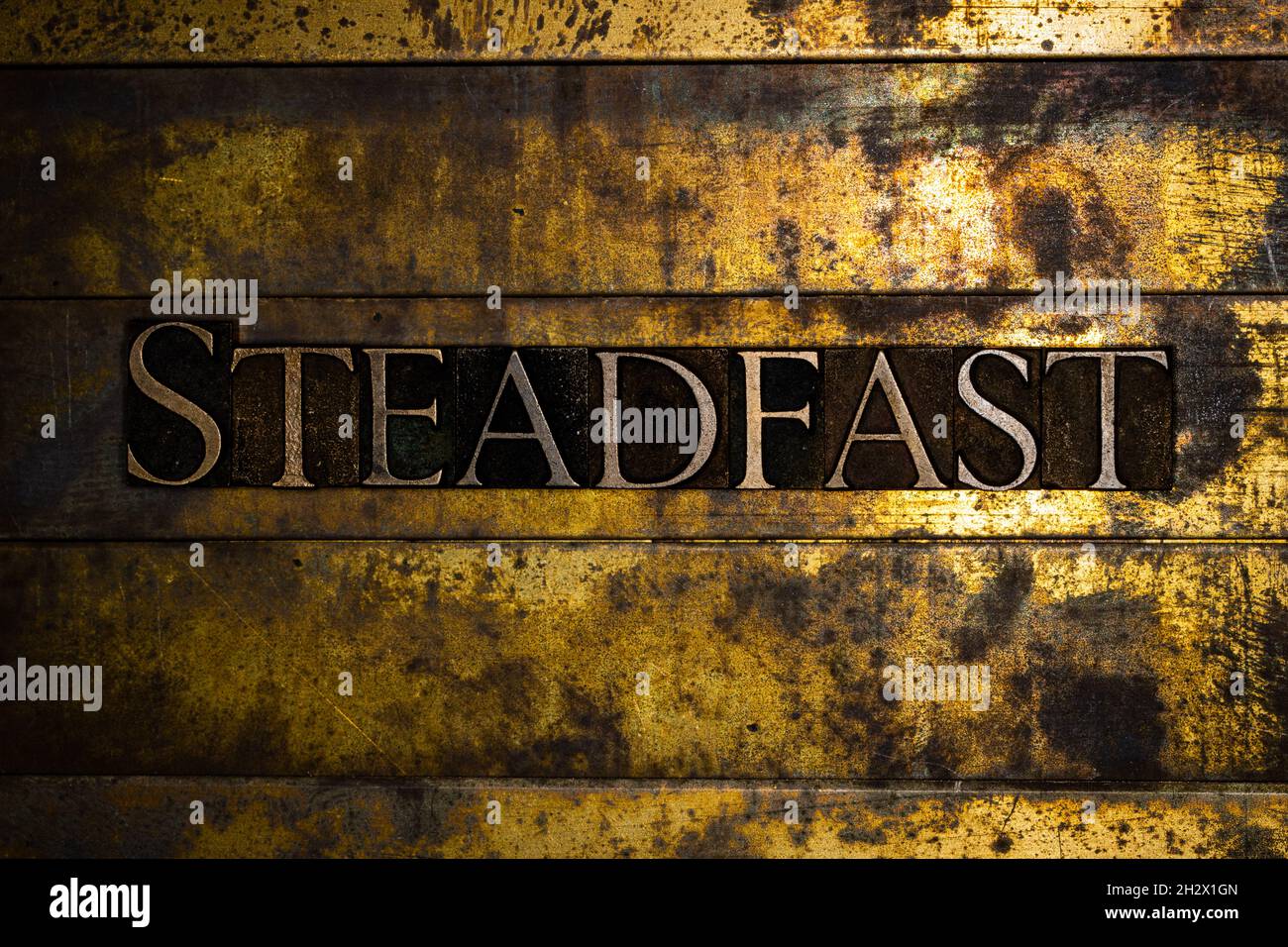 Steadfast text on textured grunge copper and vintage gold background Stock Photo