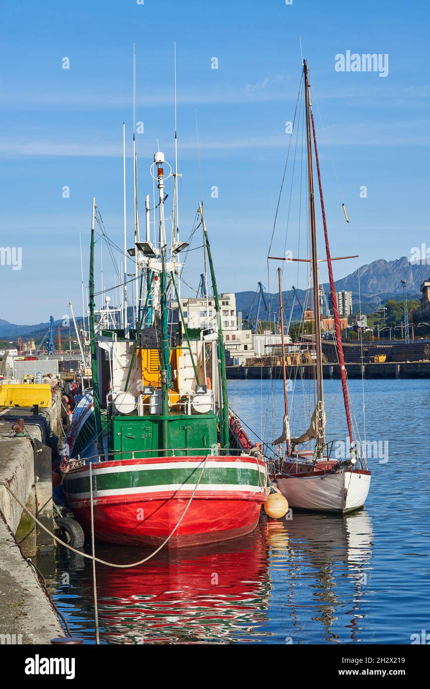 A fishing boat and a sailboat moored in the Port of Pasajes. Gipuzkoa, Spain. Stock Photo