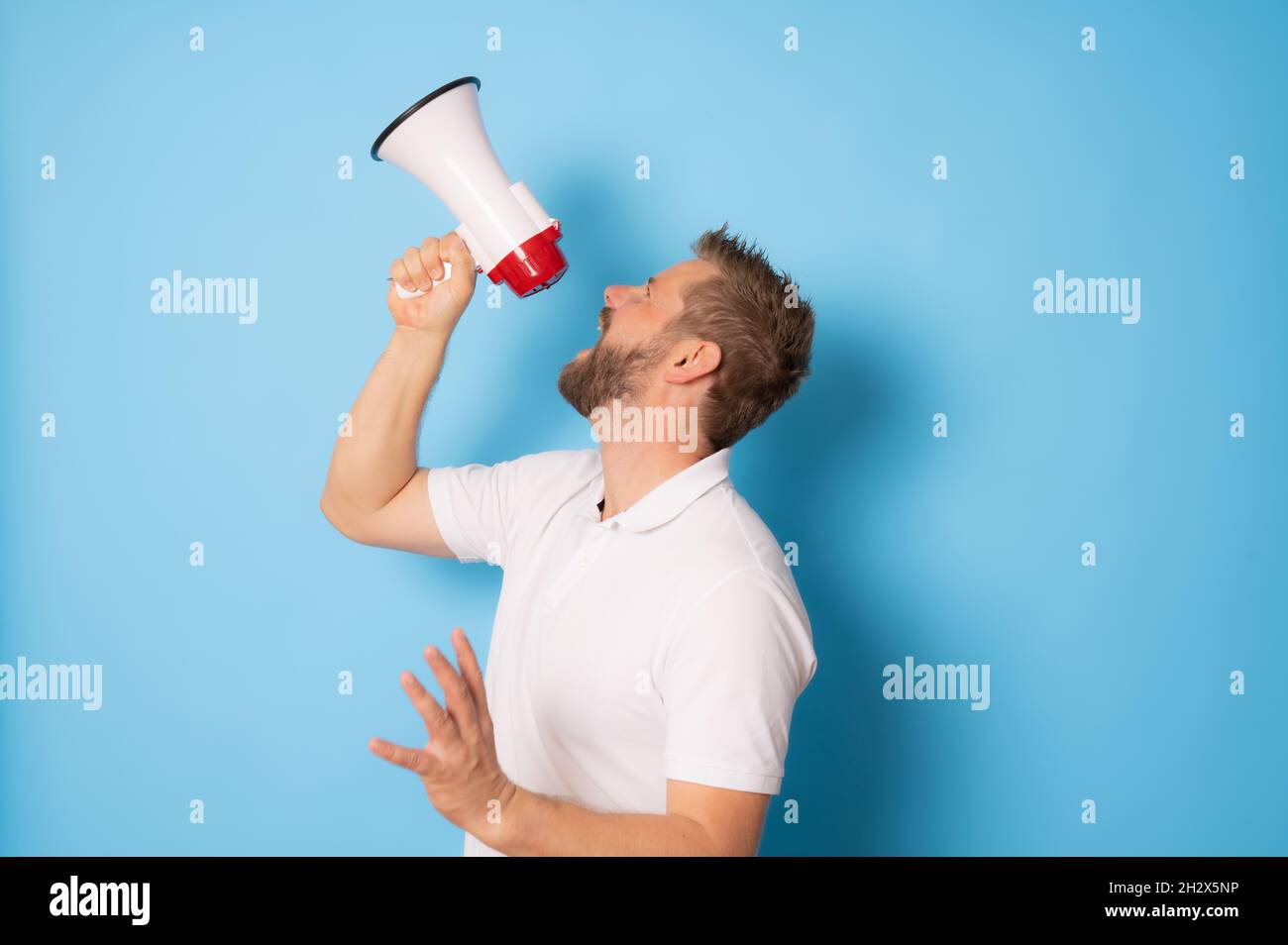 Handsome man over isolated blue wall shouting through a megaphone Stock Photo