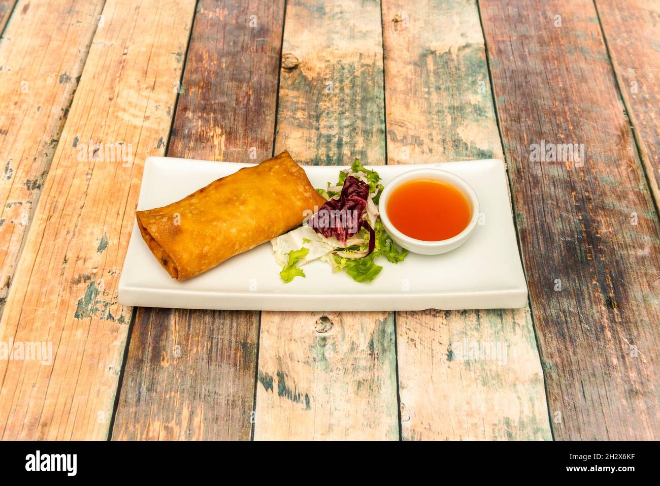 Delicious crispy spring roll stuffed with vegetables and minced meat fried in olive oil with sweet and sour sauce to garnish Stock Photo