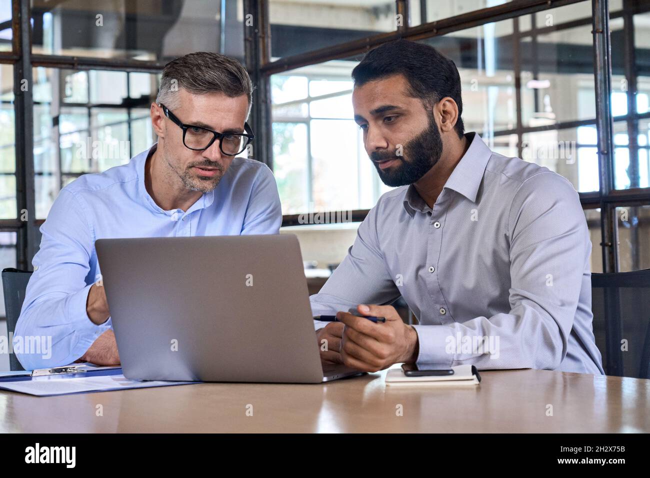 Two business men analysts discussing data management using laptop computer. Stock Photo
