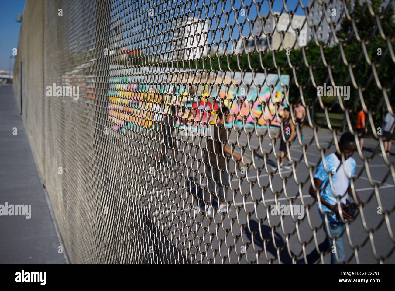 Children play basketball in enclosed court, sport at Jardins d’Éole, 20 Rue du Département, 75018 Paris, France Stock Photo