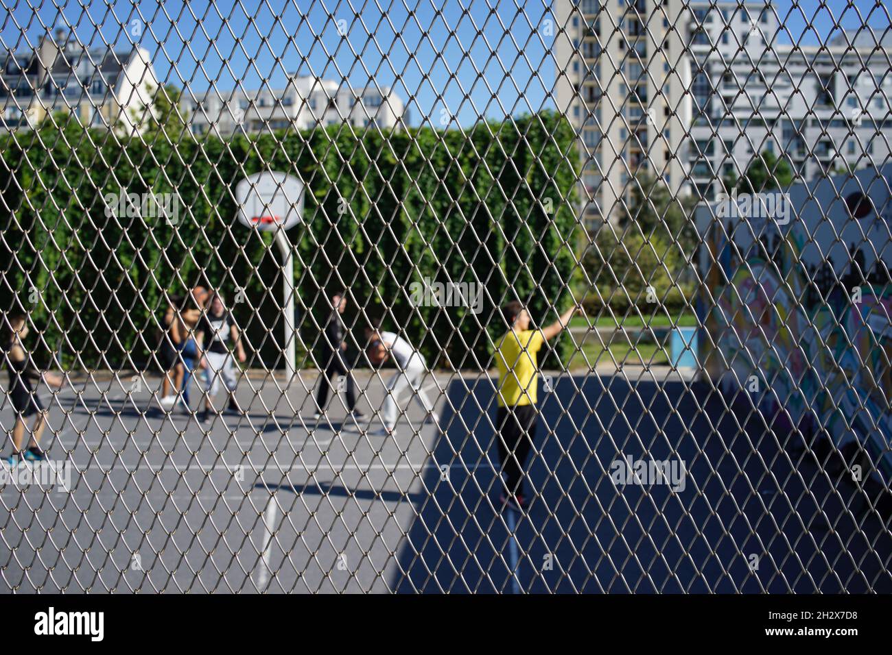 Children play basketball in enclosed court, sport at Jardins d’Éole, 20 Rue du Département, 75018 Paris, France Stock Photo