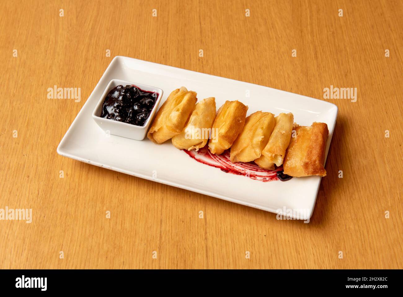 Crispy cheese fried in olive oil with blueberry jam on white plate Stock Photo