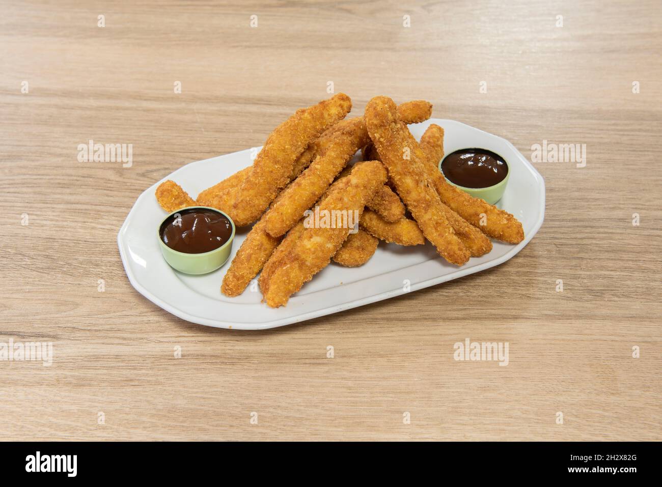 Large portion of crispy chicken strips breaded with panko and egg fried in olive oil, accompanied by barbecue sauce and served as tapas Stock Photo